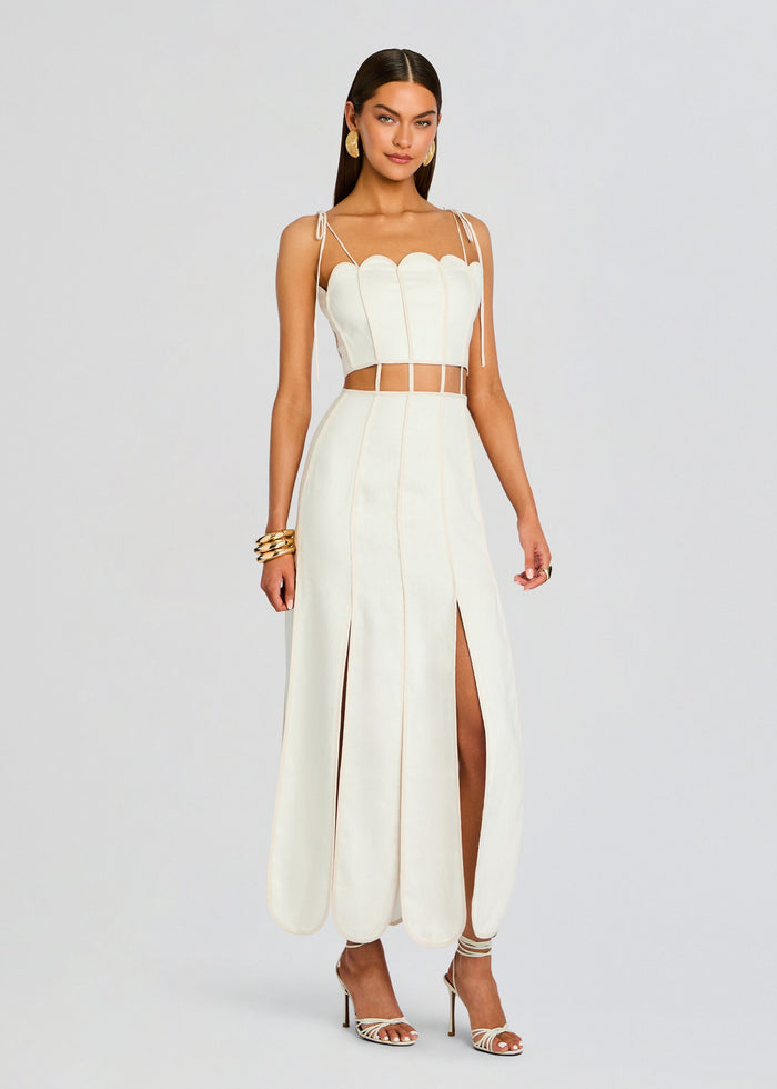 Ivory Malta Dress on model featuring scalloped top, thin shoulder ties, and a long paneled skirt with front slits. media 2 of 4