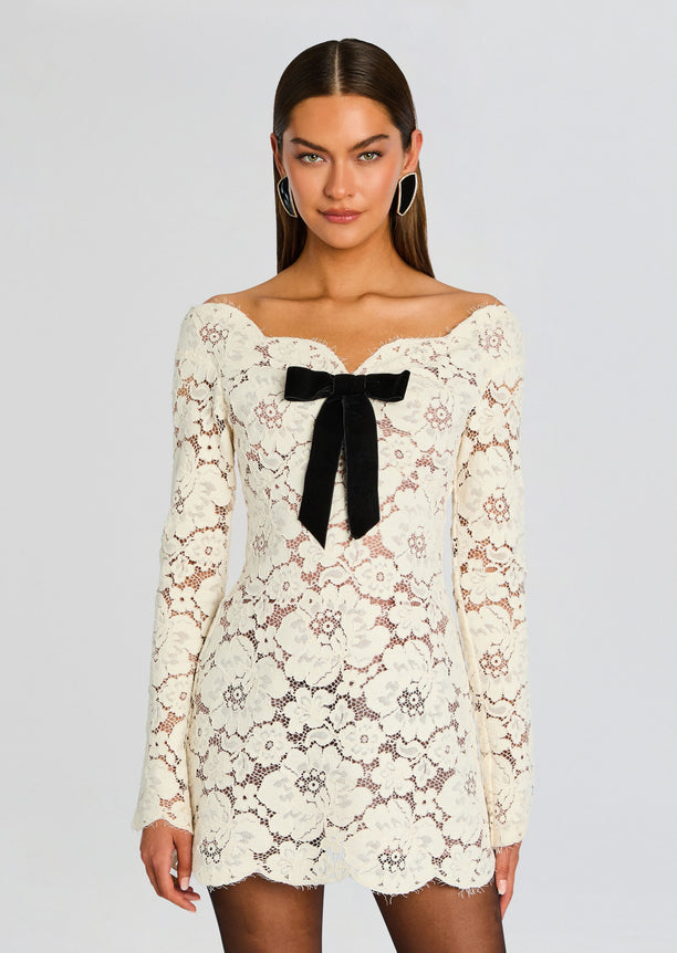 Front view of ivory floral lace mini dress with off the shoulder neckline and black satin bow at the bust