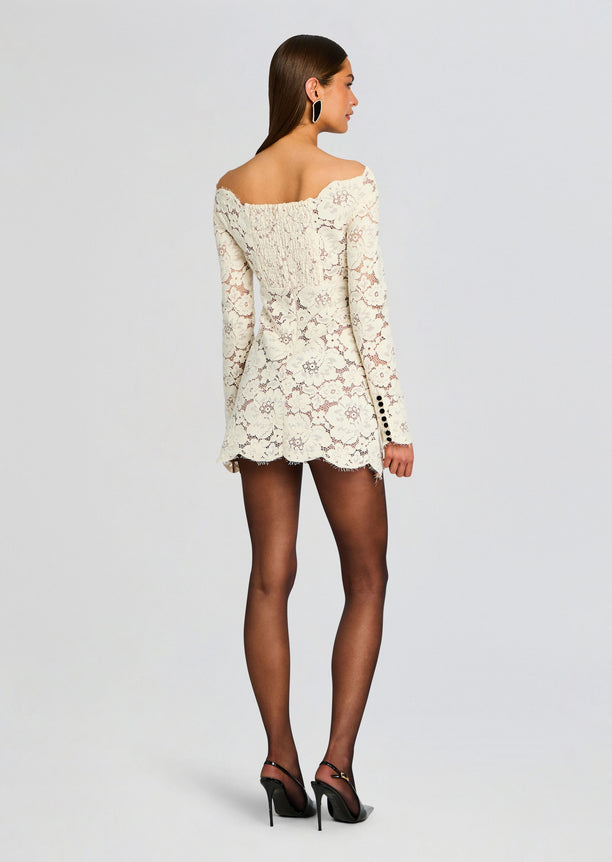Back view of an ivory lace off the shoulder mini dress with long sleeves and a scalloped hem