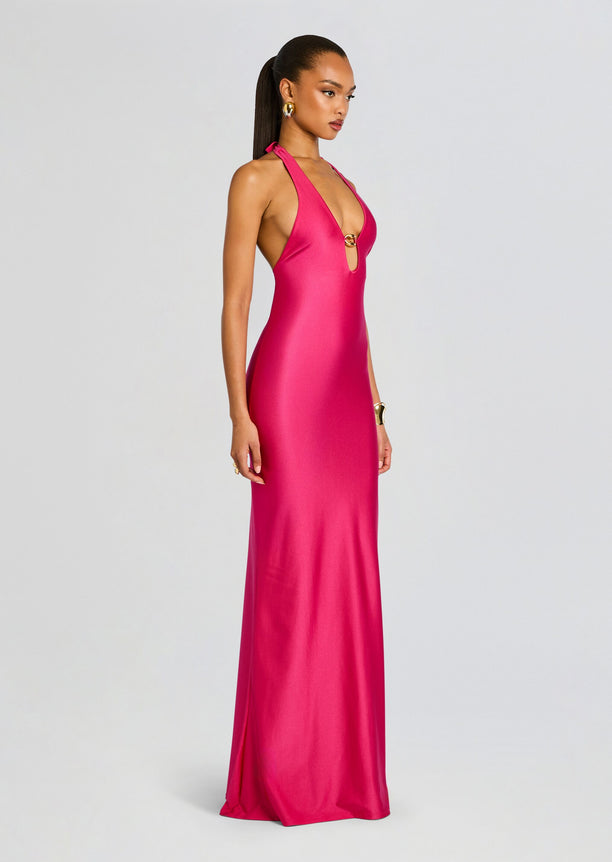 Profile view of a model wearing the Sienna Maxi Dress in bright pink a sleek halter gown.