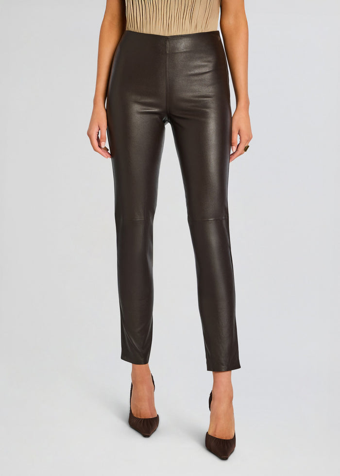 Front view of a model wearing dark brown Cyra Leather Legging with a high waist and brown heels. media 1 of 5