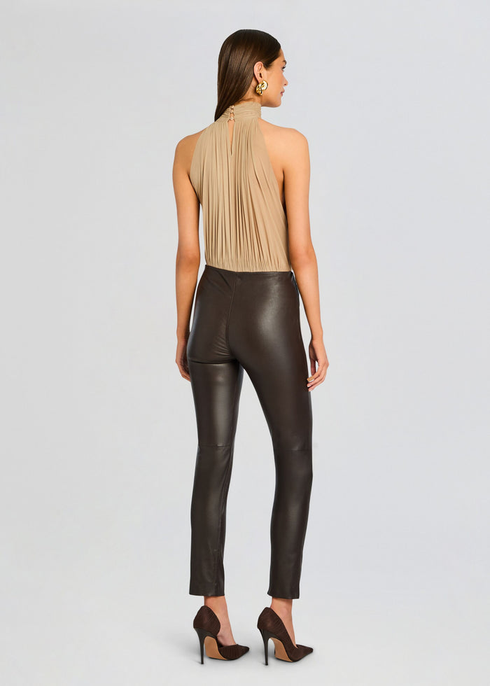 Back view of a model wearing Cyra Leather Leggings with a beige pleated halter top and brown heels. media 5 of 5