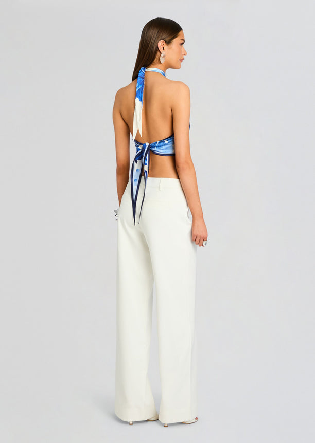 Back view of Jamie Silk Top in blue and white pattern tied at the back with white wide-leg pants.