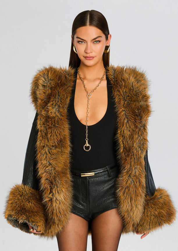 Model wearing a brown fur coat with an oversized collar and cuffs over a black ensemble.