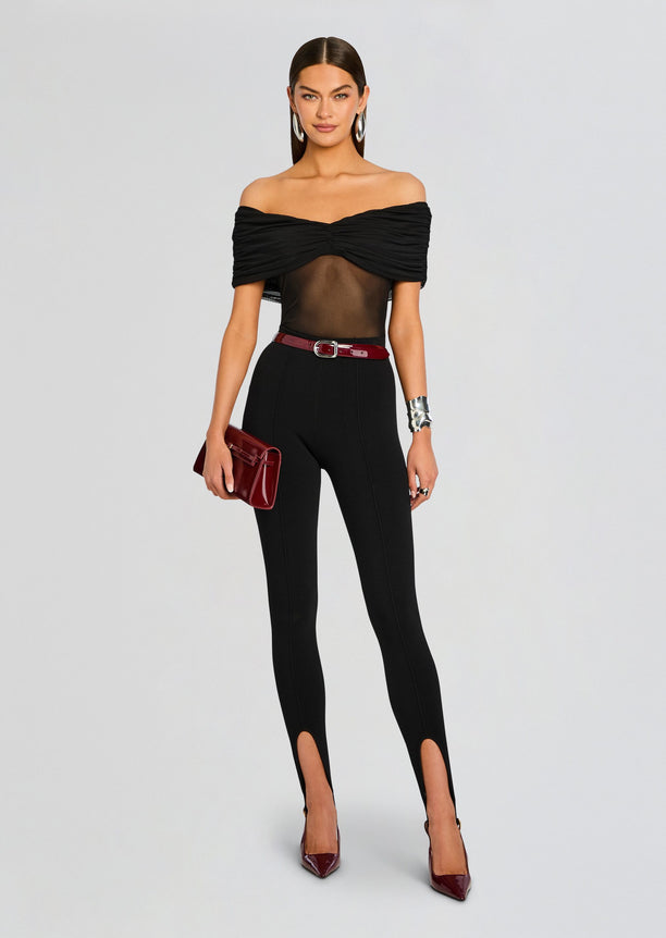 Front view of a model in black Kelsey Stirrup Leggings with off the shoulder top and statement earrings wearing burgundy heels.