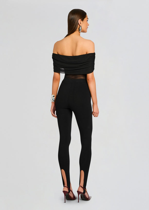 Back view of a model in black Kelsey Stirrup Leggings with off the shoulder top and a burgundy belt, holding a burgundy clutch.