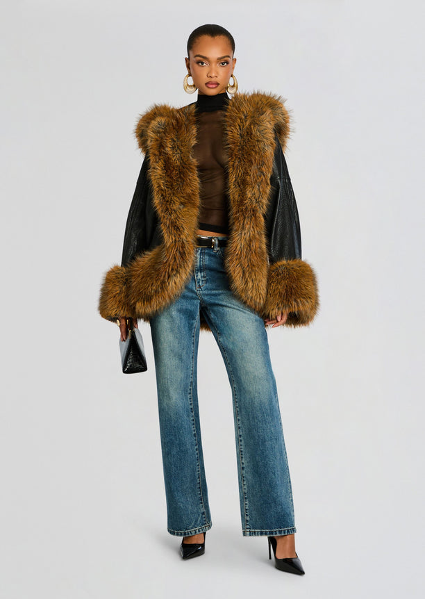 Model in a tan faux fur vest over a sheer black top and blue jeans with a black belt and black pointed heels.