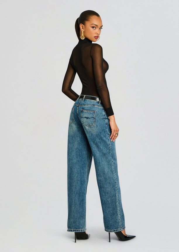 Back view of the Lainey Top a sheer black turtleneck worn with blue denim jeans and belt