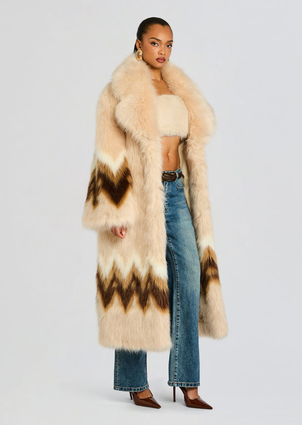 Side view of a model in a cream beige Magali faux fur coat with brown chevron pattern, paired with a cropped top and jeans.