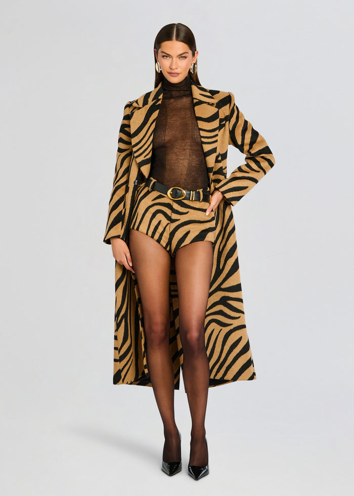 Model in a tiger print coat over a brown sheer top with matching tiger print shorts and black heels. media 2 of 5