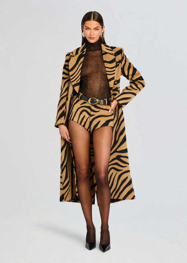 Model in a tiger print coat over a brown sheer top with matching tiger print shorts and black heels.