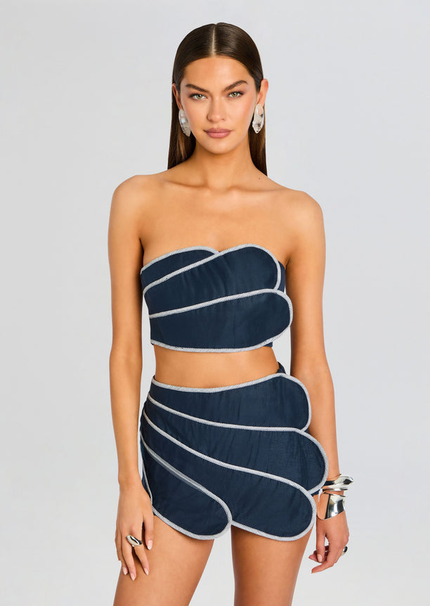 Model wearing a navy blue bandeau top with white piping.