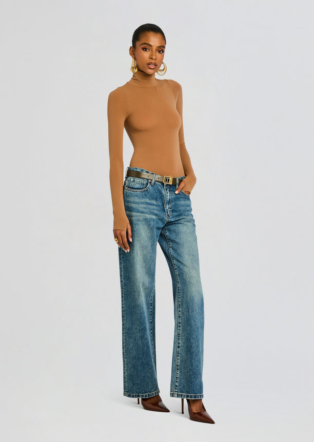 Model in tan Ballet Turtleneck Bodysuit with blue jeans and a belt, accessorized with large gold hoop earrings