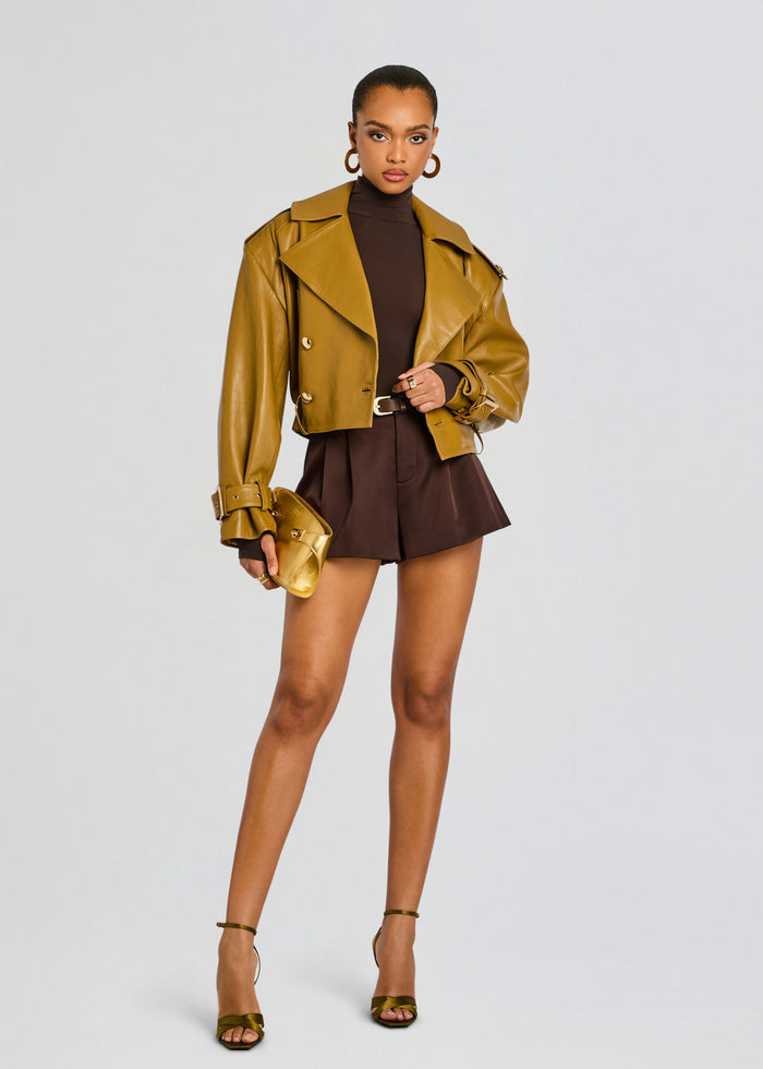 Model wearing a tan cropped leather jacket over a dark brown turtleneck bodysuit and matching high waisted brown shorts. media 6 of 6