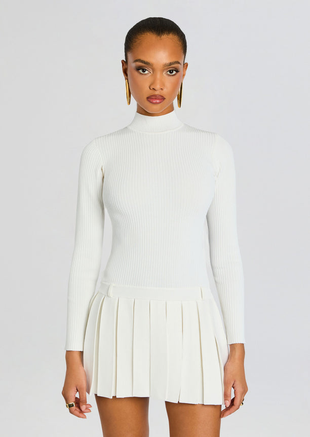 Front view of a white ribbed knit dress with a high neckline and pleated mini skirt.