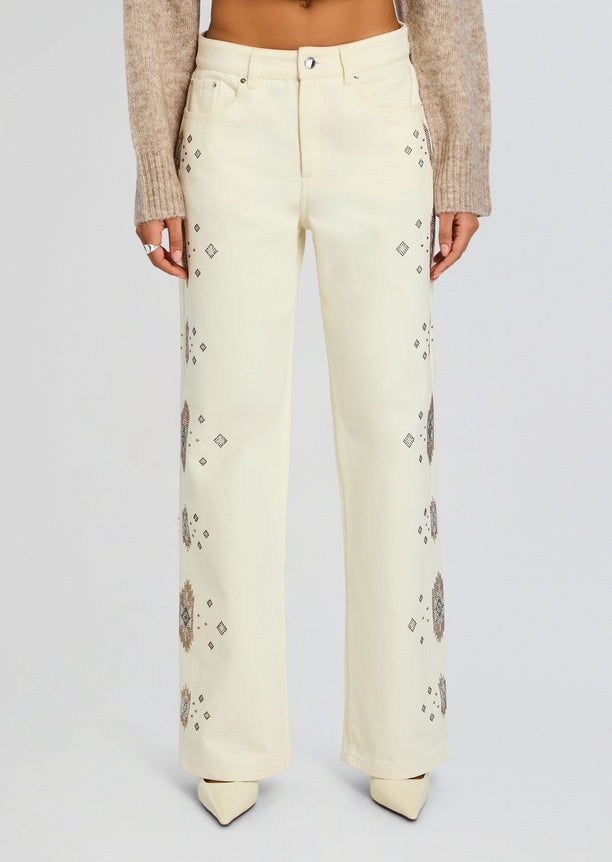 Front view of pale cream high-waisted jeans with scattered diamond embroidery along the legs.