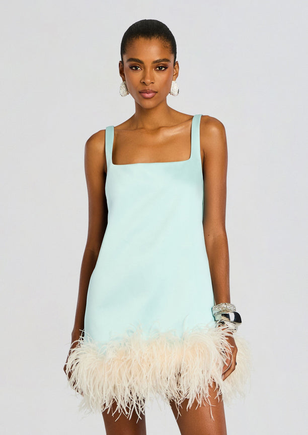 Model wearing a pastel mint Ragna Feather Dress with wide straps and a fluffy feathered hem.