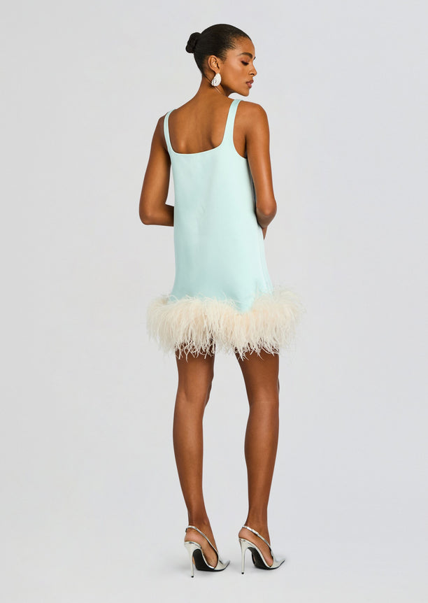 Back view of a model in a mint Ragna Feather Dress with shoulder straps and fluffy feather hem, wearing silver stiletto sandals.