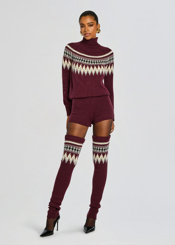 Model wearing a burgundy Rocky Knit Romper with a ribbed knit silhouette and knee high patterned socks. media 1 of 5