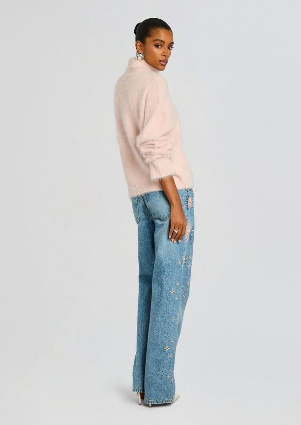 Side view of a model in a pale pink fuzzy sweater wearing Vero Embroidered Jean with pink embroidery along the leg.