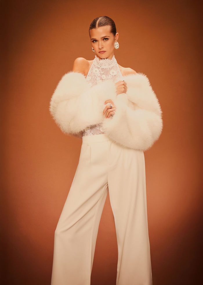 Saga Lace Embellished Bodysuit styled with white wide-leg pants and a fluffy white fur stole against a warm backdrop. media 2 of 6