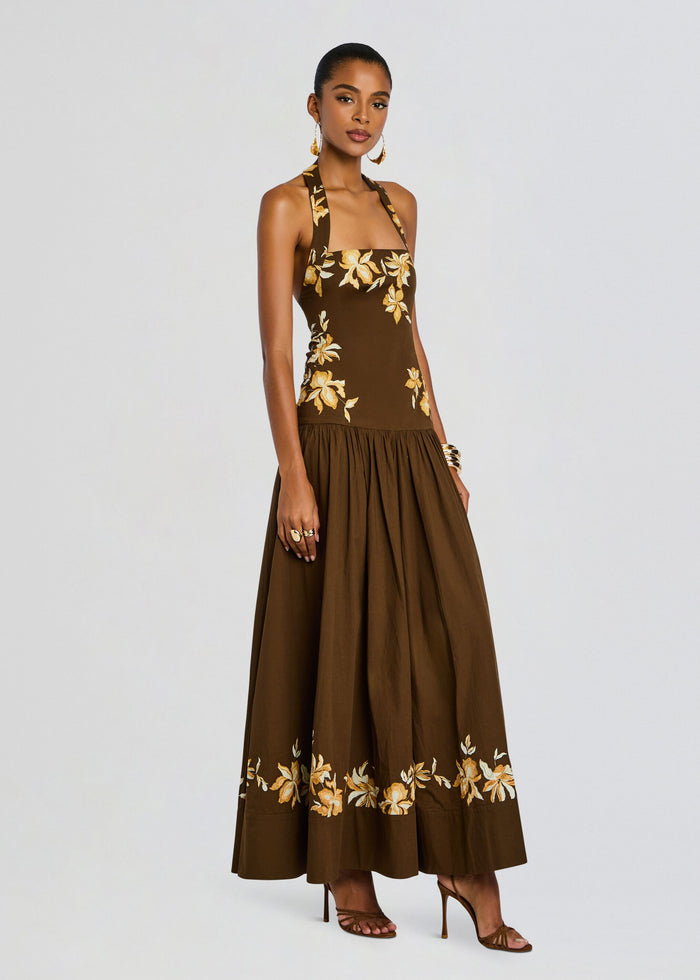 Model wearing brown halter maxi dress with gold floral embroidery on bodice and hem, wearing heeled sandals. media 3 of 5