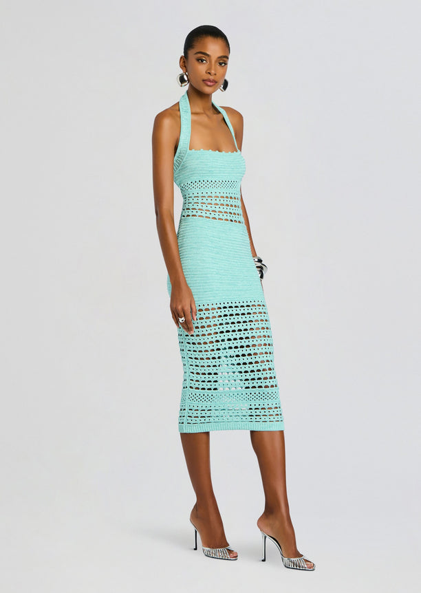 Model wearing turquoise crochet dress with halter neckline and openwork midsection, paired with high heels.