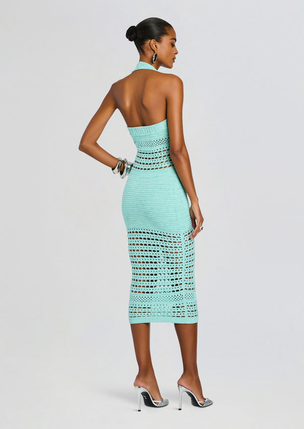 Back view of turquoise crochet dress on model with halter neck, exposed back and open crochet panels at the waist and skirt.