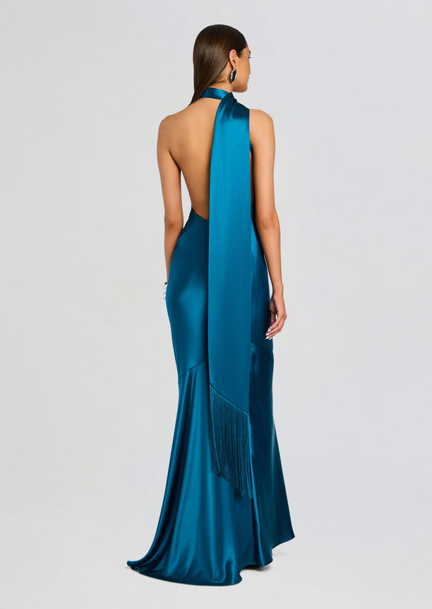 Back view of teal satin Kelsa Dress with open back and long fringe scarf cascading down the skirt.