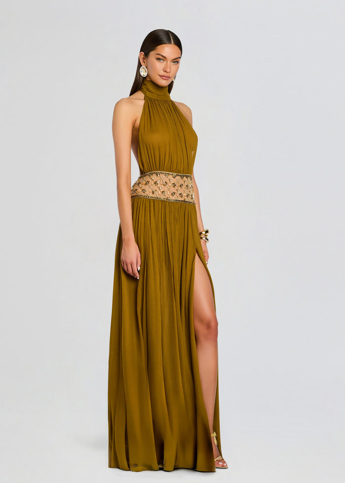 Model wearing Kreeli Embellished Dress with mustard halter neck and a beaded waist, flowing pleated skirt. media 3 of 5