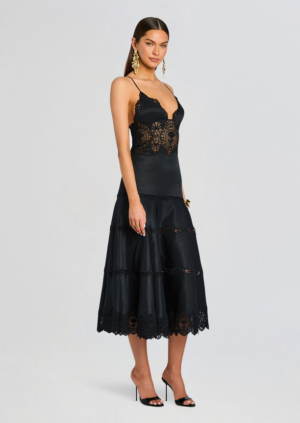 Model wearing Leilani Dress in black with lace bodice and tiered midi skirt, gold statement earrings.