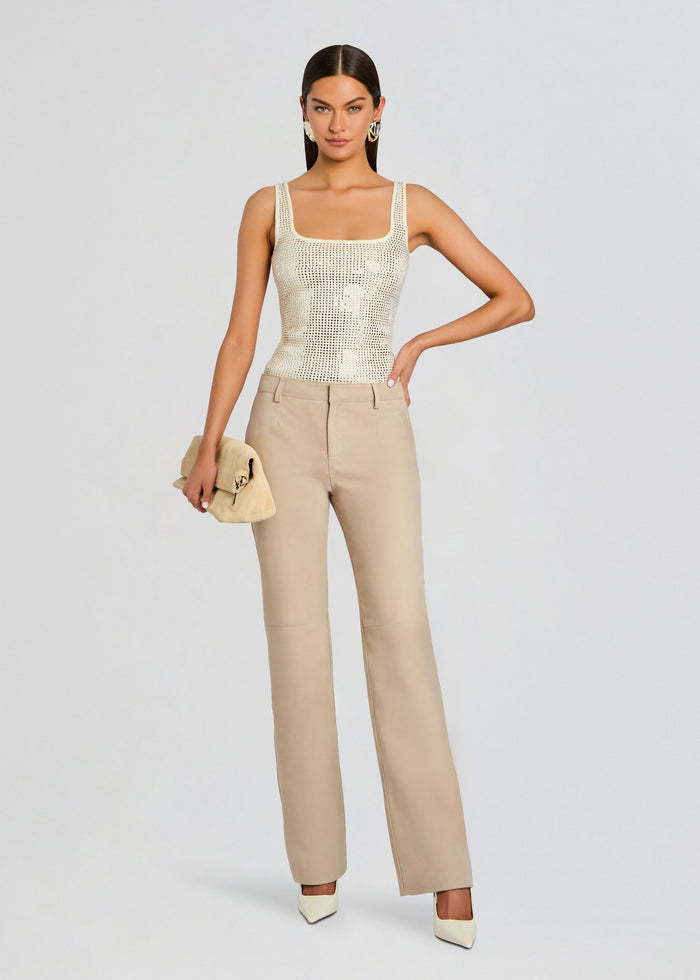 Model wearing the cream embellished tank top with beige tailored trousers and a beige clutch media 2 of 5