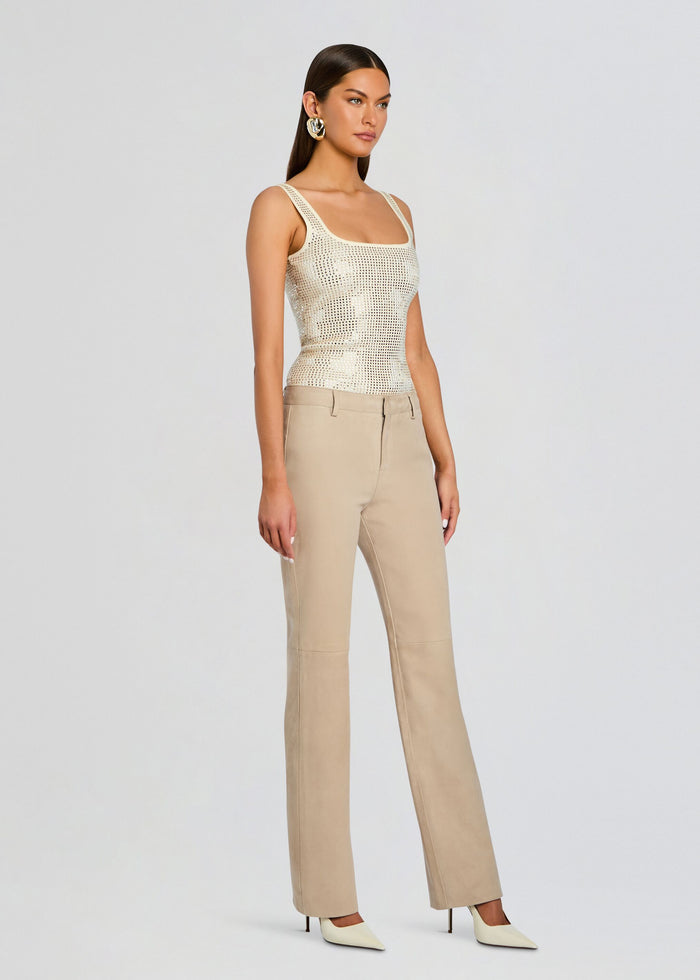 Model wearing a cream embellished top with wide straps and square studs, paired with beige tailored pants media 4 of 5