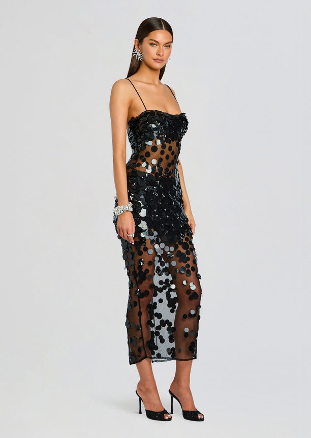 Model wearing Mischa Sequin Dress with black circular sequins over sheer mesh in a midi length