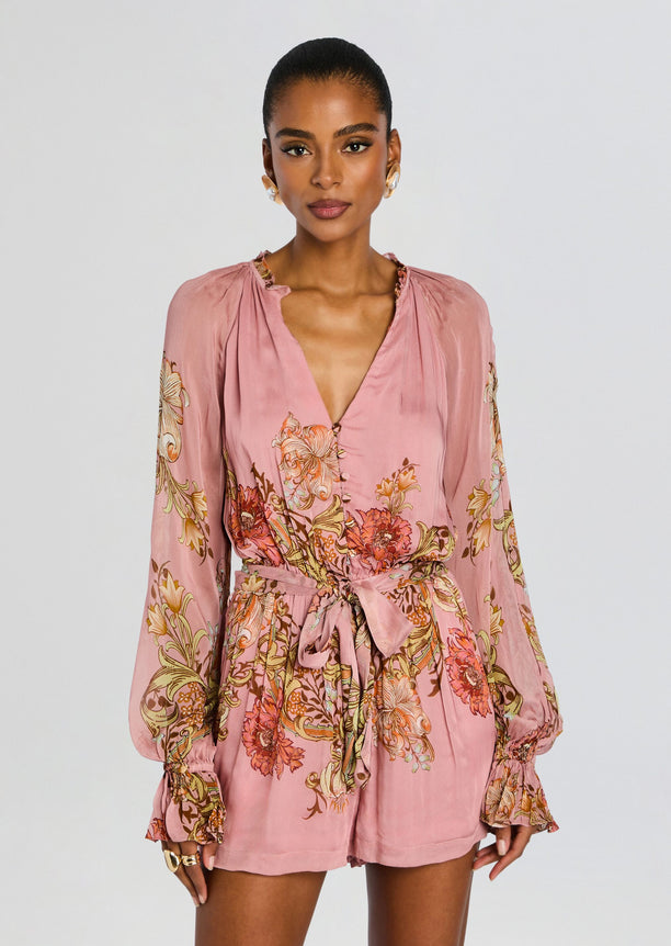 Front view of pink Sula romper with waist tie belt and bold floral print on the sleeves