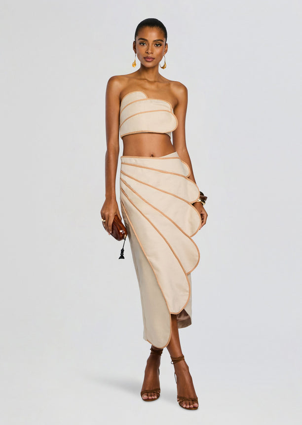 Side view of beige bandeau top and sculpted wrap skirt with peach piping.