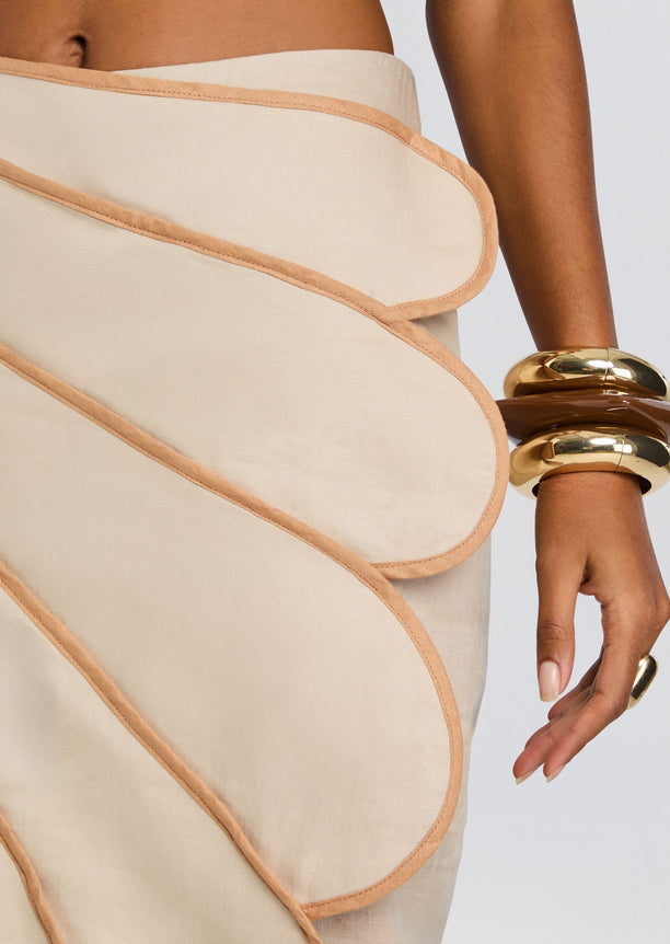 Beige Sango skirt close up shows peach curved trim outlining layered petals.