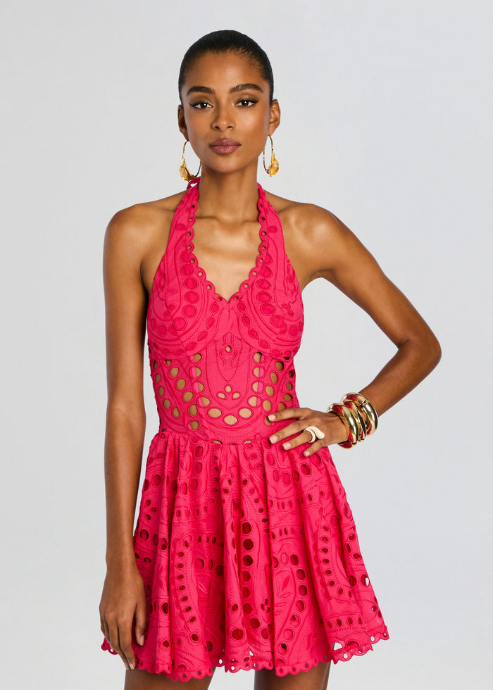 Front view of a model wearing a hot pink Sandlight Short Dress with halter neck and bold eyelet embroidery, accessorized with gold bangles. media 5 of 5