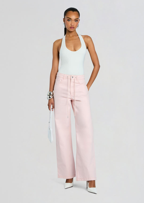 Model wearing pale pink Astrid Denim Pant with light blue halter top and white heels
