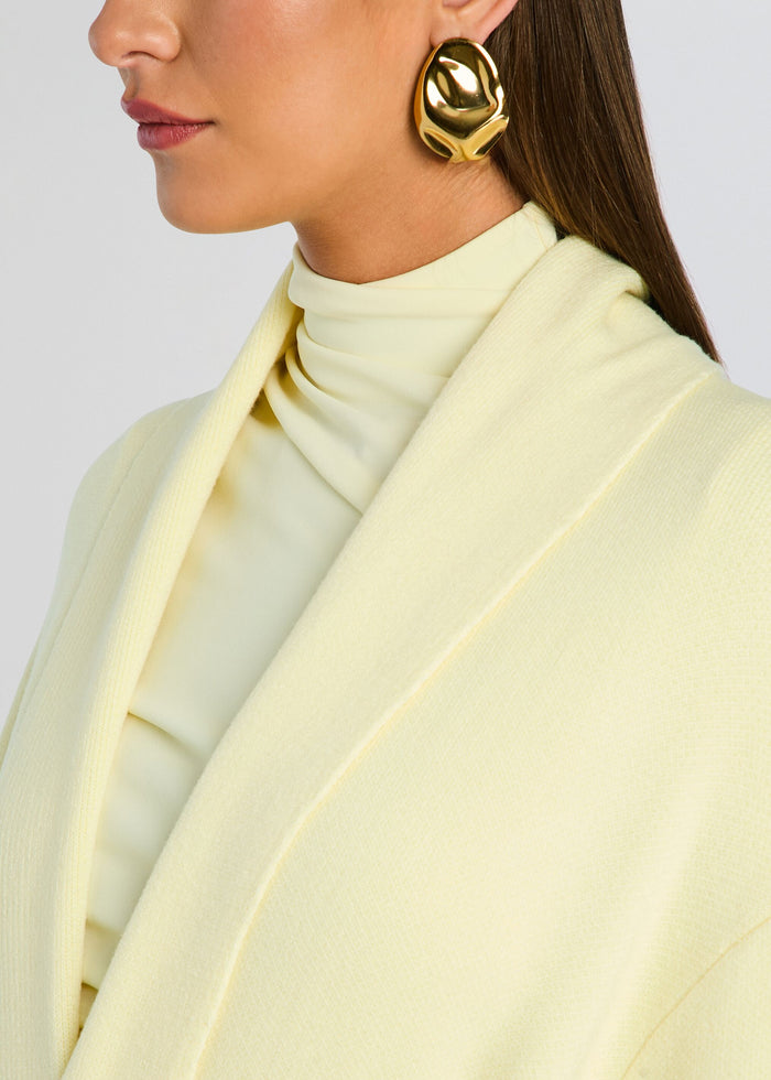 Close-up of the Crosby Sweater Duster fabric and lapel in pale yellow with a model wearing a bold gold earring. media 2 of 5
