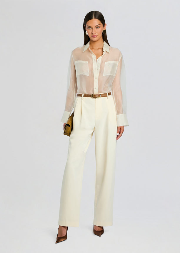 Full-length look of Estella Silk Top tucked into ivory wide-leg pants with a brown belt and clutch.