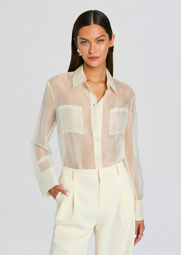 Model wearing sheer cream Estella Silk Top with two front pockets and long sleeves.