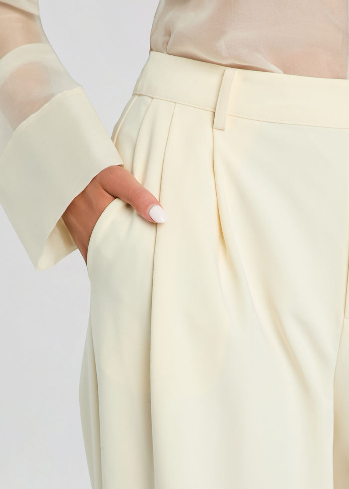 Close-up of the Sonya Pant waist showing belt, pleats, and pocket details with a hand in the pocket. media 3 of 5