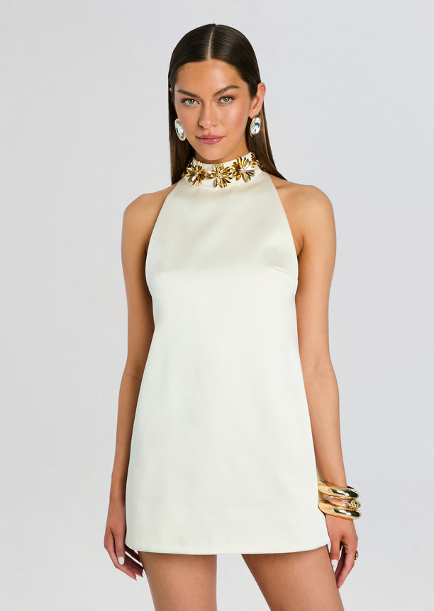 Cream halter mini dress with a gold floral neckline embellishment on a model.