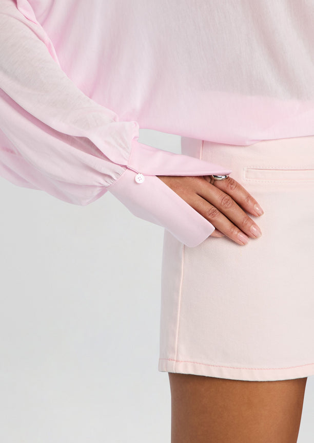 Hawkes bodysuit sleeve in soft pink with a white buttoned cuff resting on a matching pale pink skirt