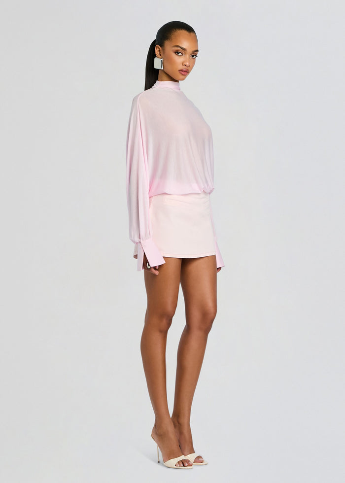 Full length side view of a model wearing a pale pink Hawkes bodysuit tucked into a mini skirt with high heels media 4 of 5