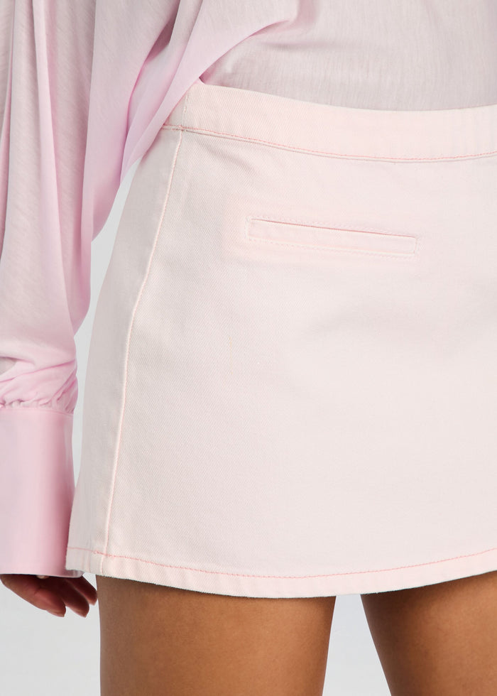 Close up of pale pink denim mini skirt waist showing a back welt pocket and pink topstitching media 3 of 5