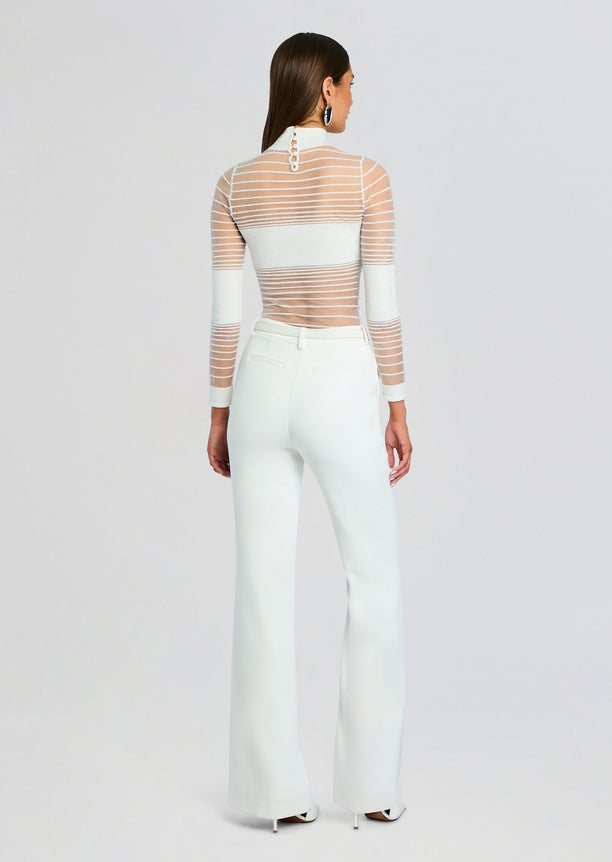 Back view of Katrine Top showing sheer striped mesh with white underlayer and white high waisted pants
