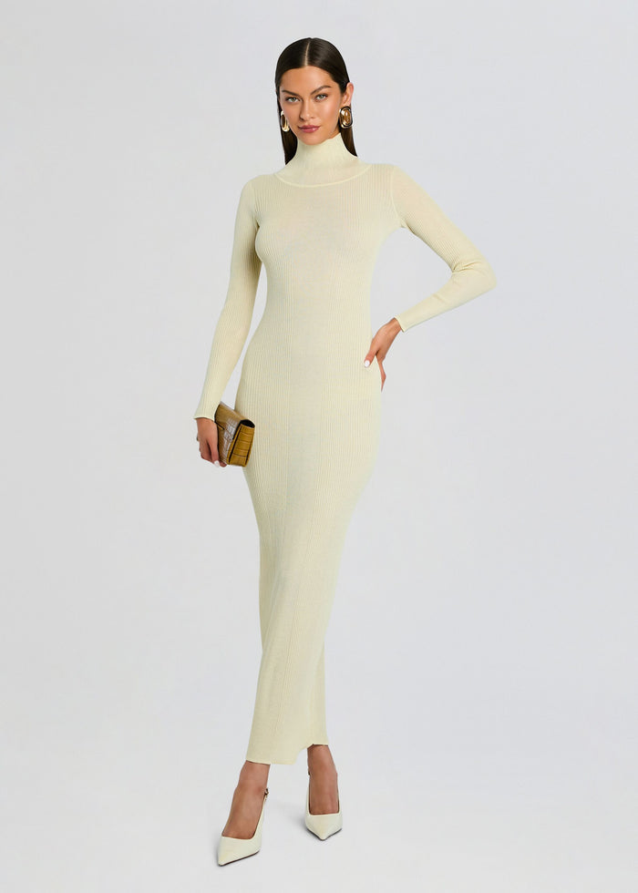 Front view of model in cream Maurice knit maxi dress with turtleneck, holding a brown clutch and wearing white heels media 5 of 5