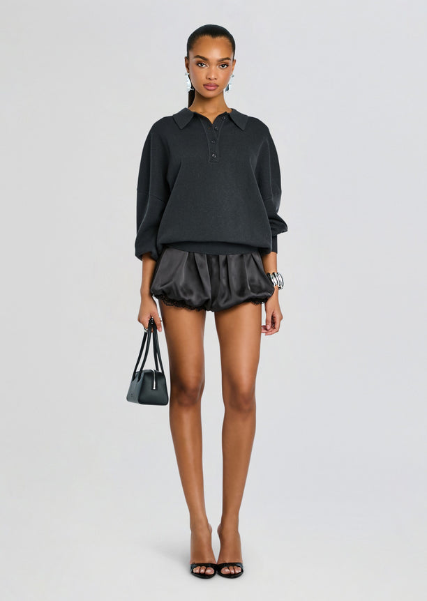 Full-body view of the Vespen Sweater outfit with an oversized dark gray sweater satin shorts and black heeled sandals.